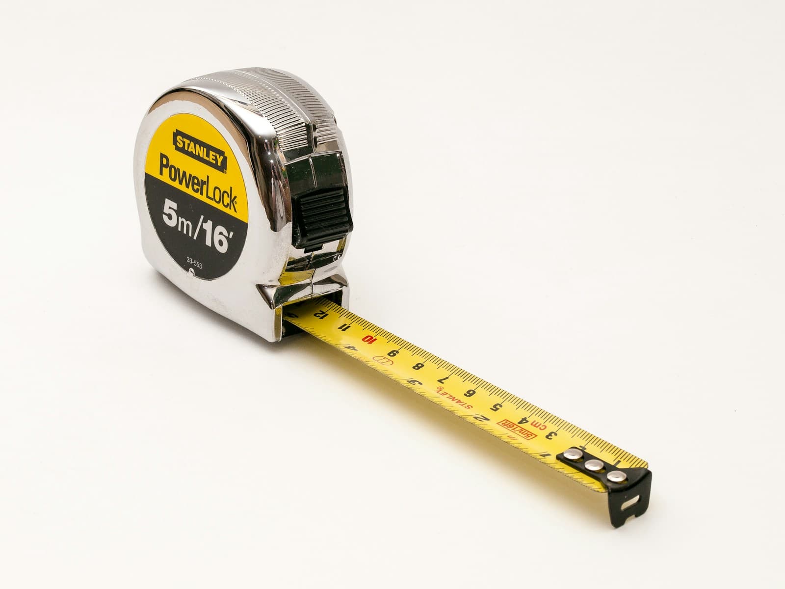 A steel tape measure extended on a white surface, showing the centimetre scale