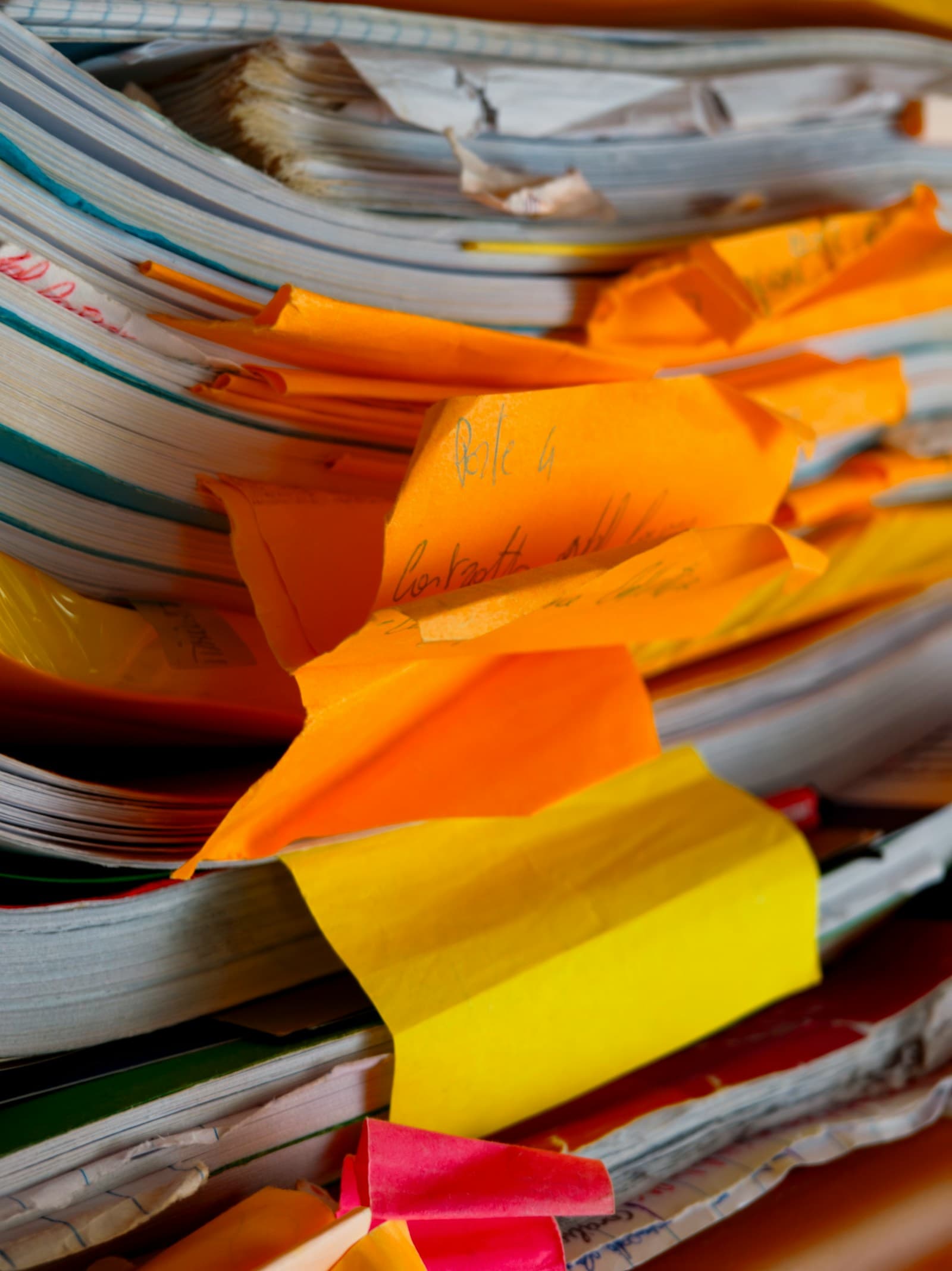 A tall, messy stack of paper folders and handwritten notes, the kind of unstructured documentation teams usually start with